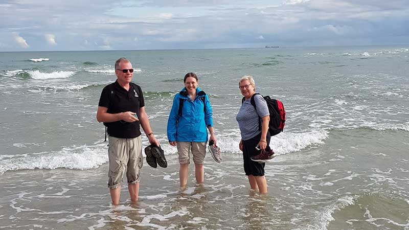 Resenärer från Tjörnarpsbuss njuter av vattnet vid Grenen i Skagen nära Haven under bussresan