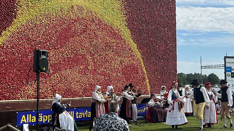 Ett folkdanslag har uppvisning framför äppeltavlan. Det är många som underhåller under äppeldagarna i Kivik.