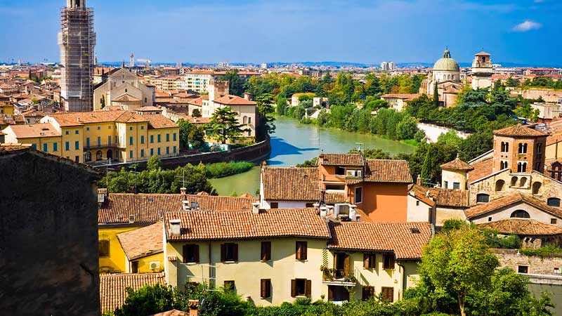 Panoramavy över Verona i Italien med Adige-floden, historiska byggnader, kyrktorn och grönskande omgivningar