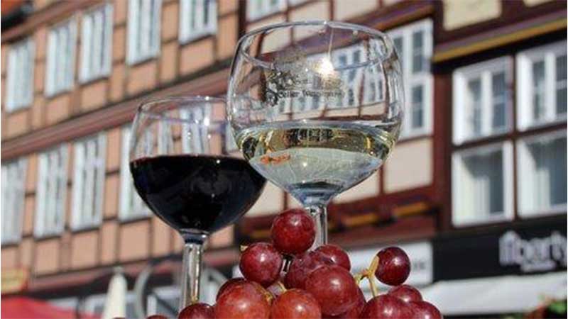 vackra korsvirkeshus i bakgrunden och vinglas i förgrunden på en uteservering under en vinresa till Celle med Tjörnarpsbuss.