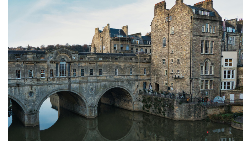 Historiska Pulteney Bridge i Bath, England, med byggnader längs bron och reflektioner i floden Avon – klassisk fotopunkt.